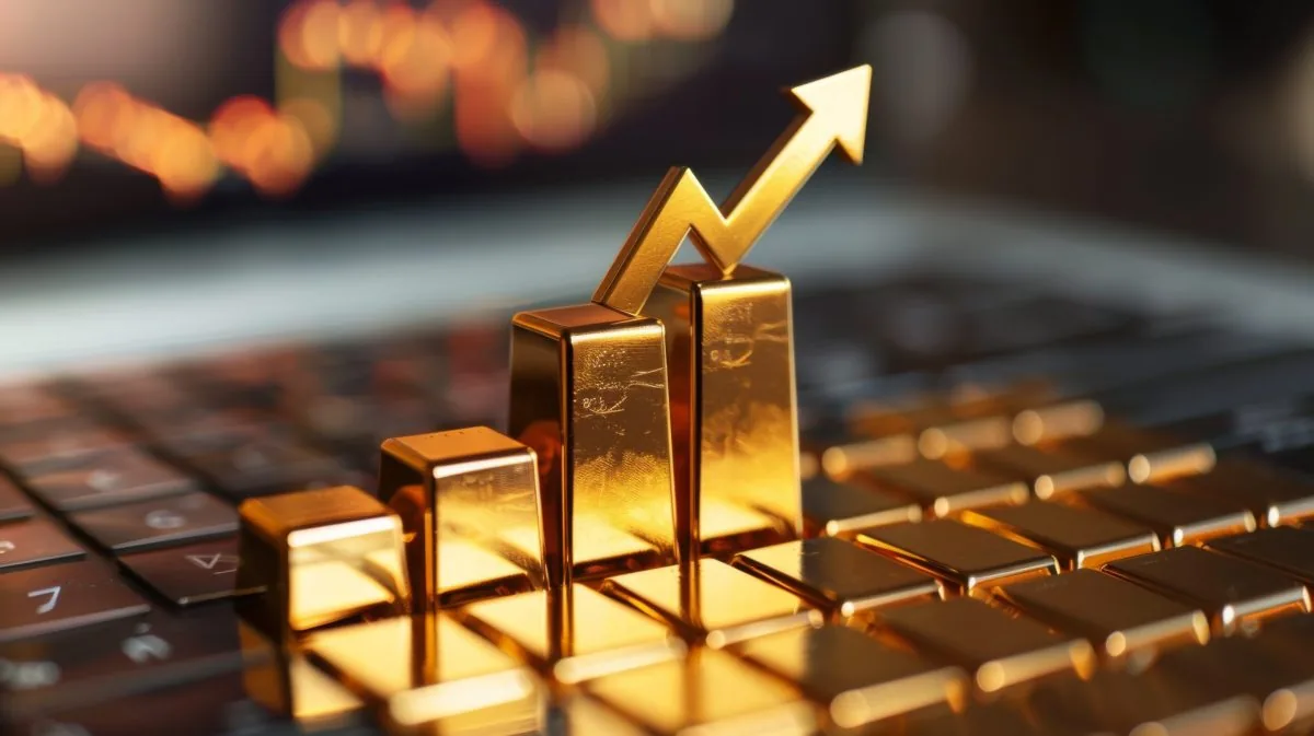 Gold bars on a keyboard with an upward arrow symbolizing growth.
