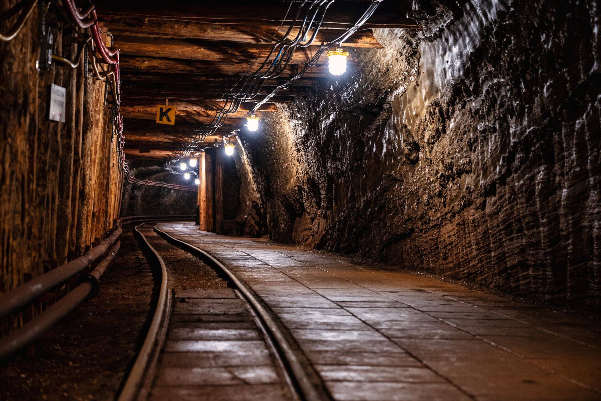 Underground mining tunnel with dim lighting and railway tracks along the floor, showcasing a well-maintained mining environment.