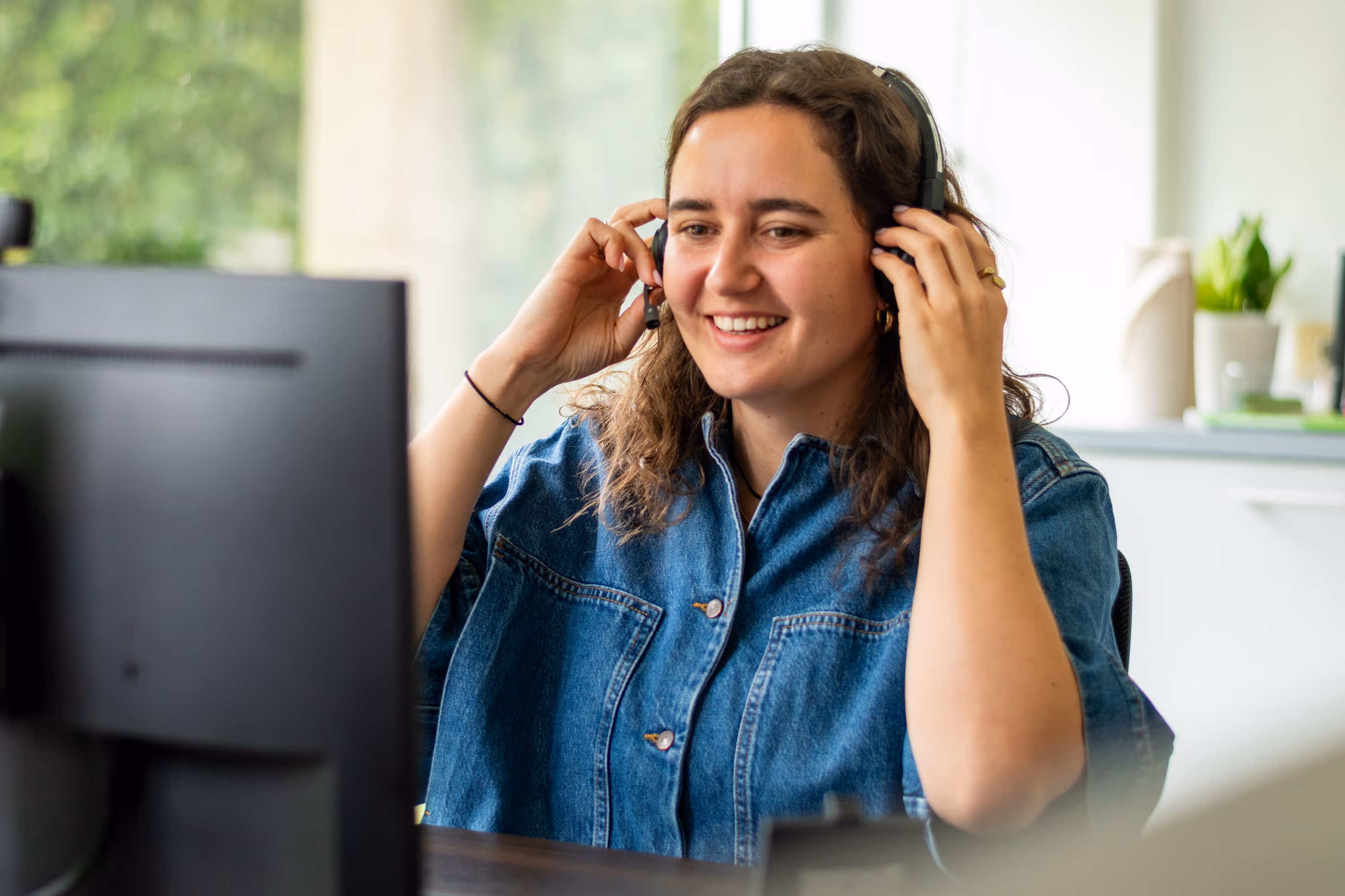 Een vrouwelijke begeleider neemt haar headset vast en lacht enthousiast.