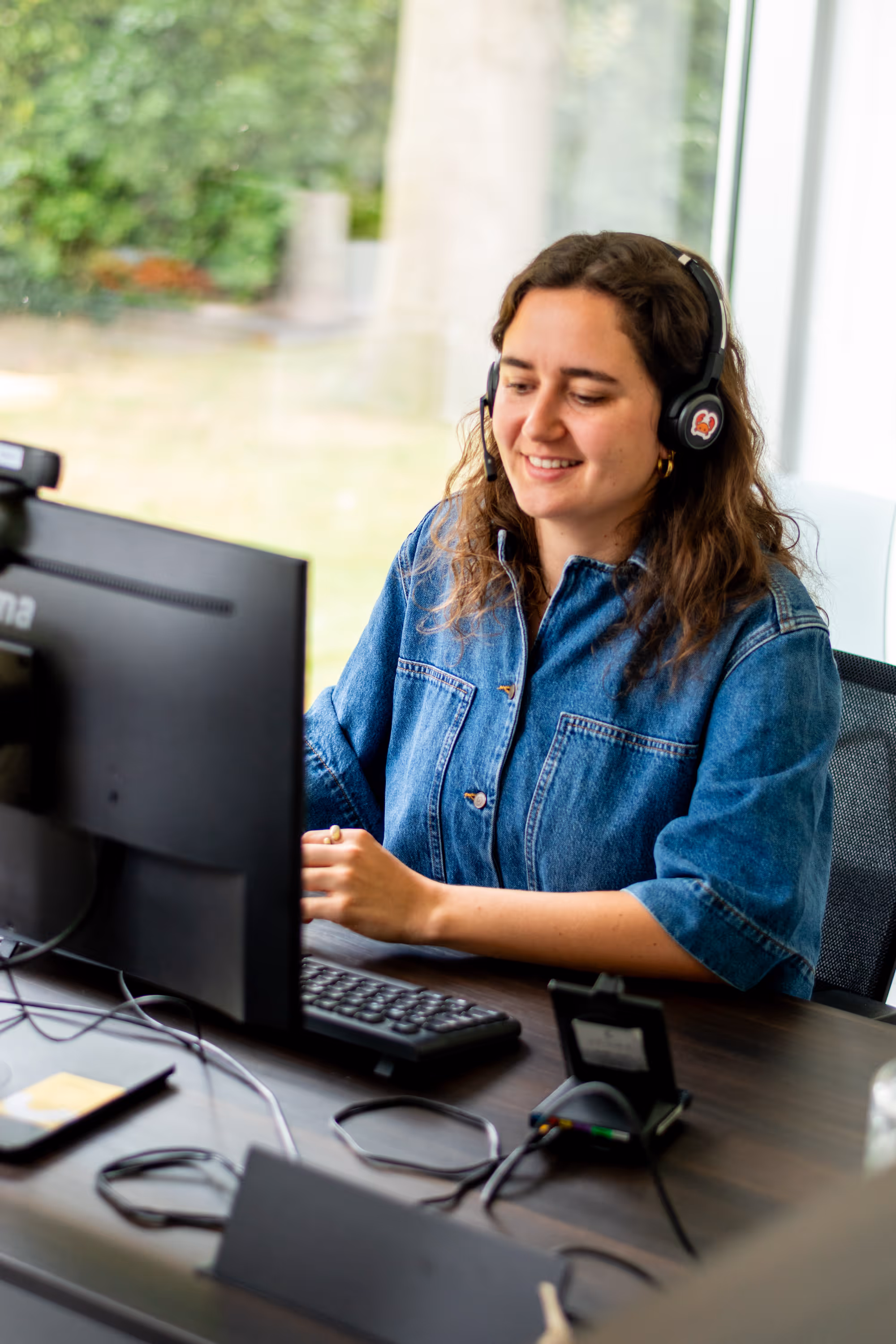 Een vrouwelijke hulpverlener met een headset bezig met een videochat.