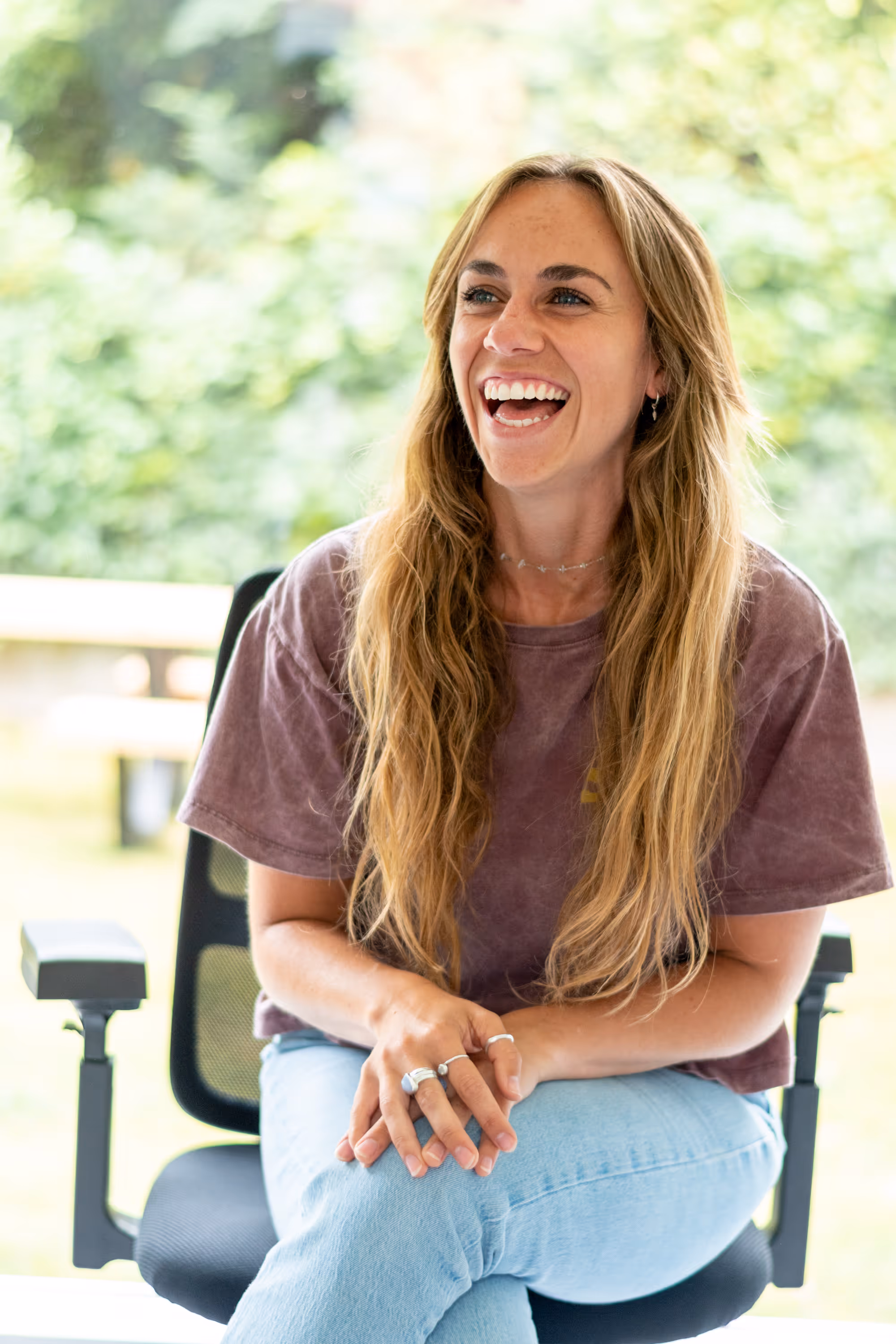 Een vrouwelijke begeleider van my24/7 die enthousiast aan het lachen is.