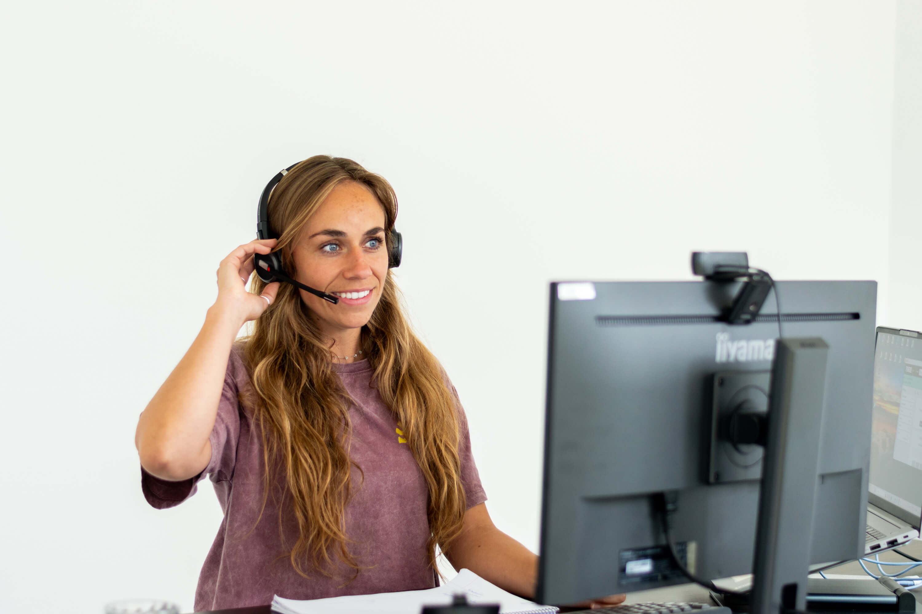 Een vrouwelijke zorgprofessional met een koptelefoon met het microotje naar haar mond gericht.