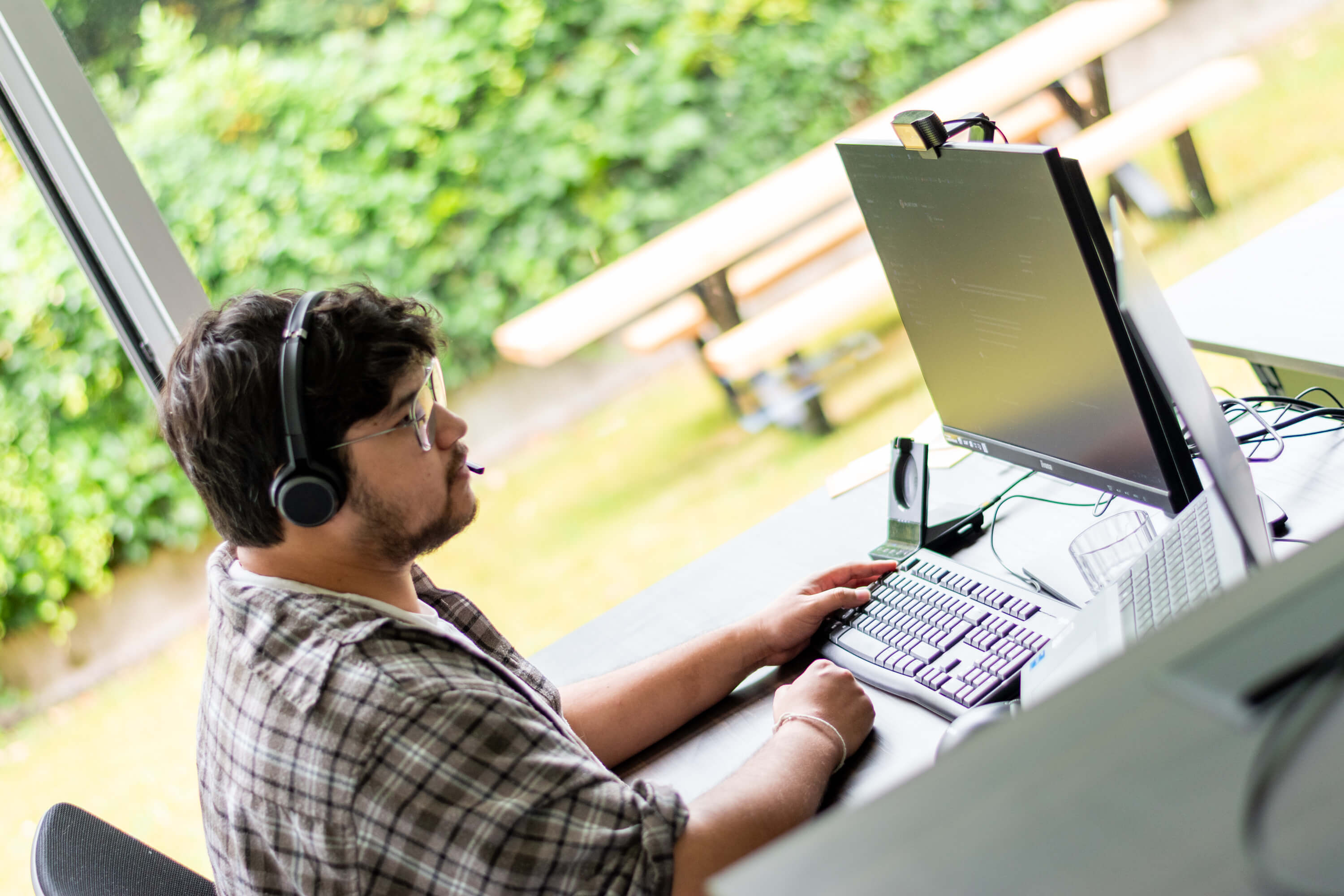 Een mannelijke zorgprofessional met een koptelefoon op die naar zijn computerscherm kijkt.