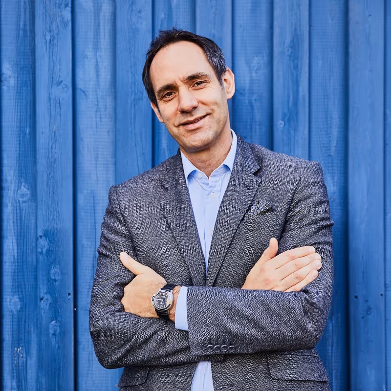 A man wearing a gray suit and a blue shirt.