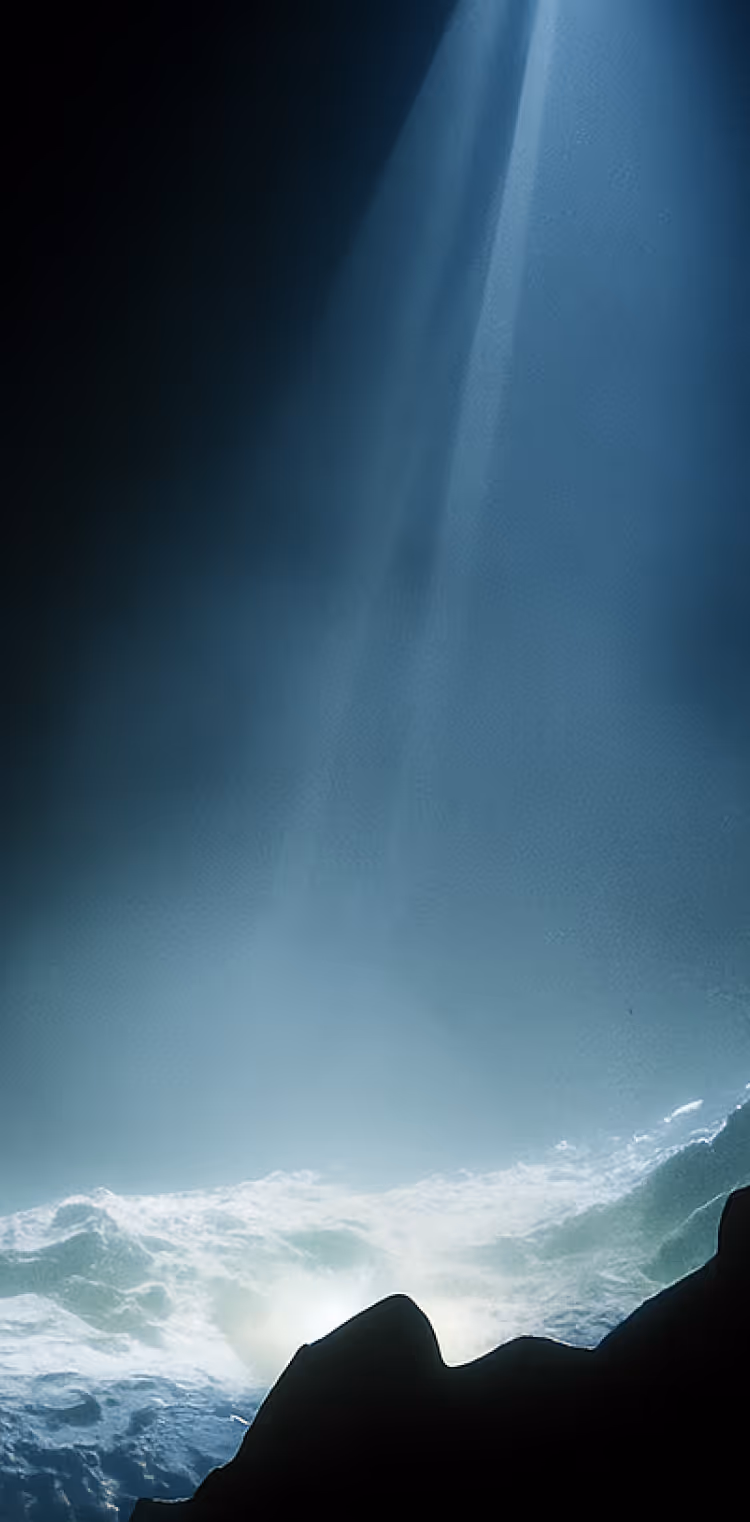 Sunlight beams penetrating underwater with silhouetted rock formations in foreground.