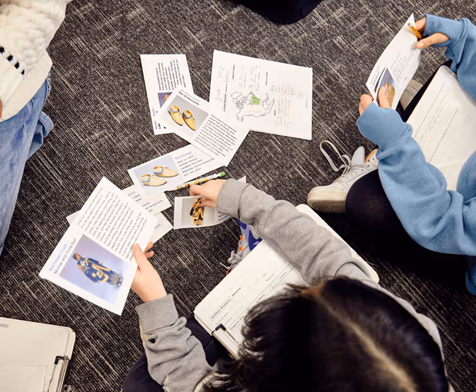 closeup of students working on a project while sat on the floor