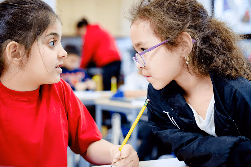 two young students sat close to each other and talking