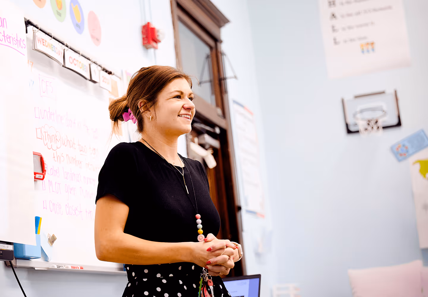 teacher smiling and standing at the front of the class