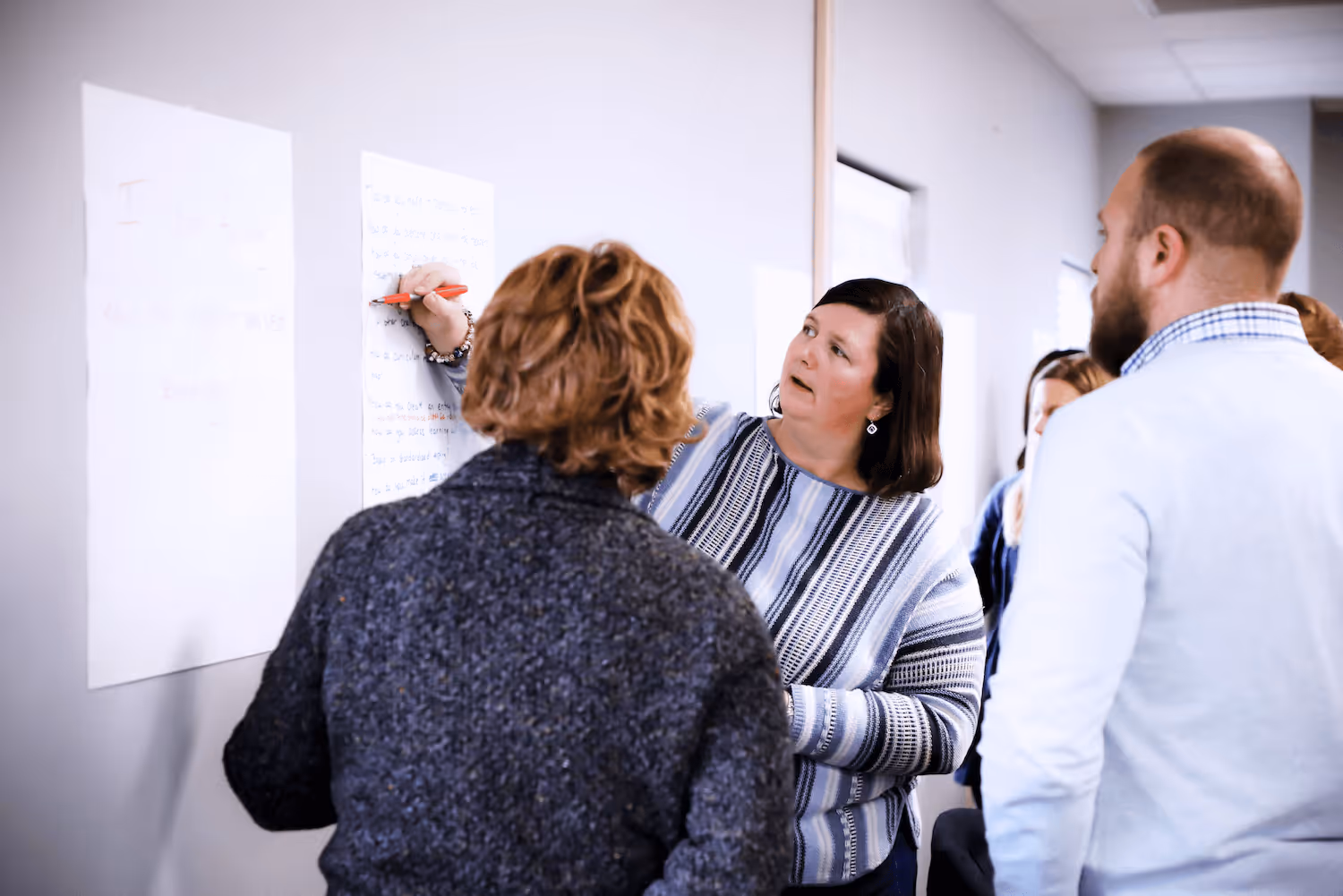 two teachers writing on a paper on the whiteboard