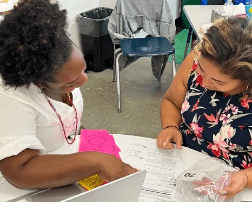 Two teachers working together at a table with lesson materials