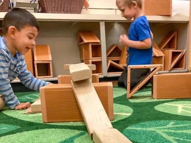Pre-K children building with wooden blocks and ramps