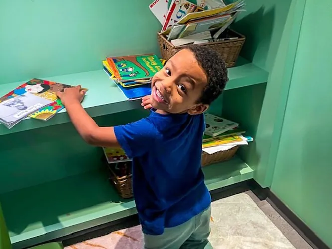 A child organizing books on a classroom shelf