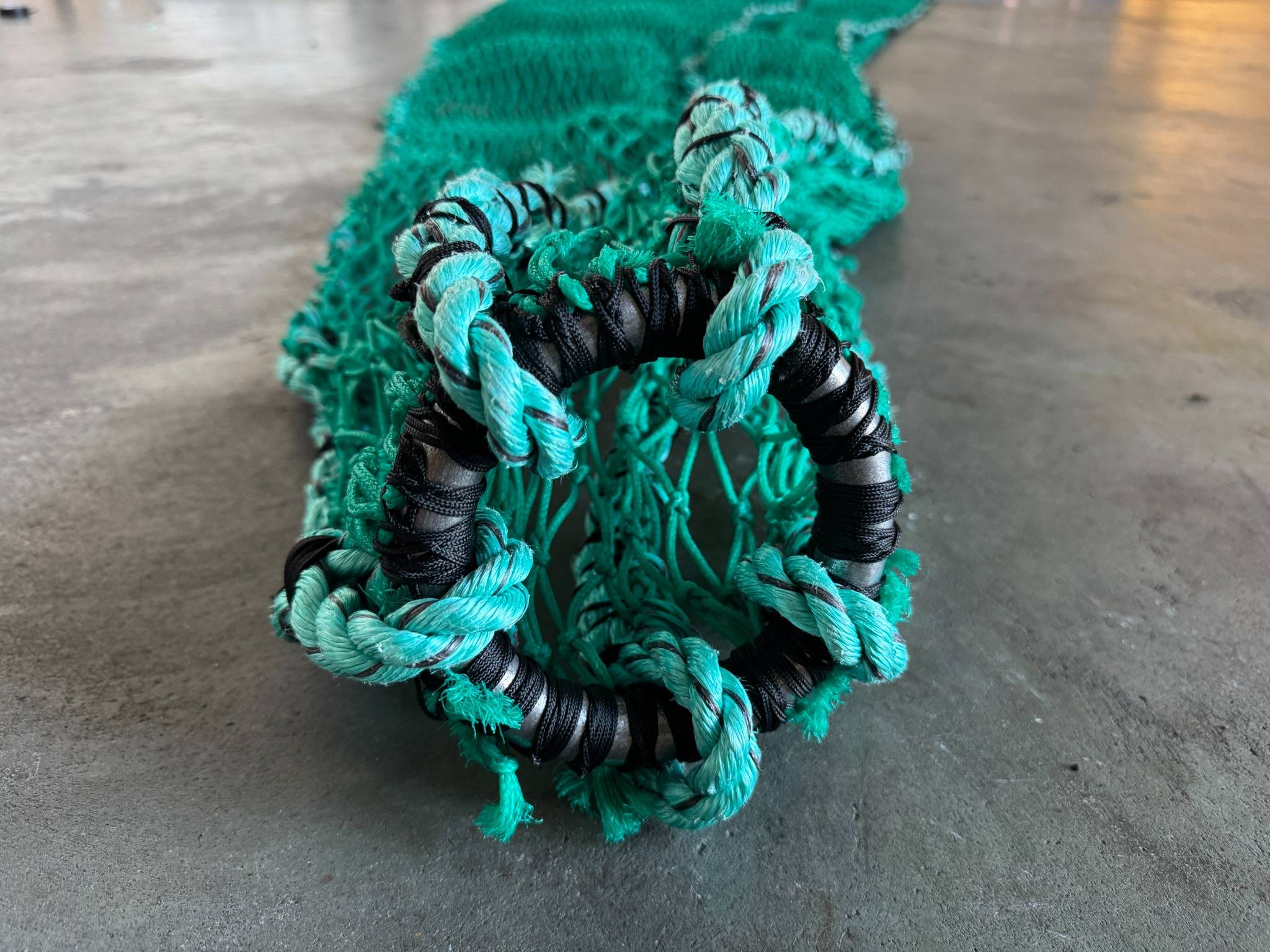 Close-up of a protective spiny dogfish net with reinforced rope and knots, designed to prevent shark damage to aquaculture cages.