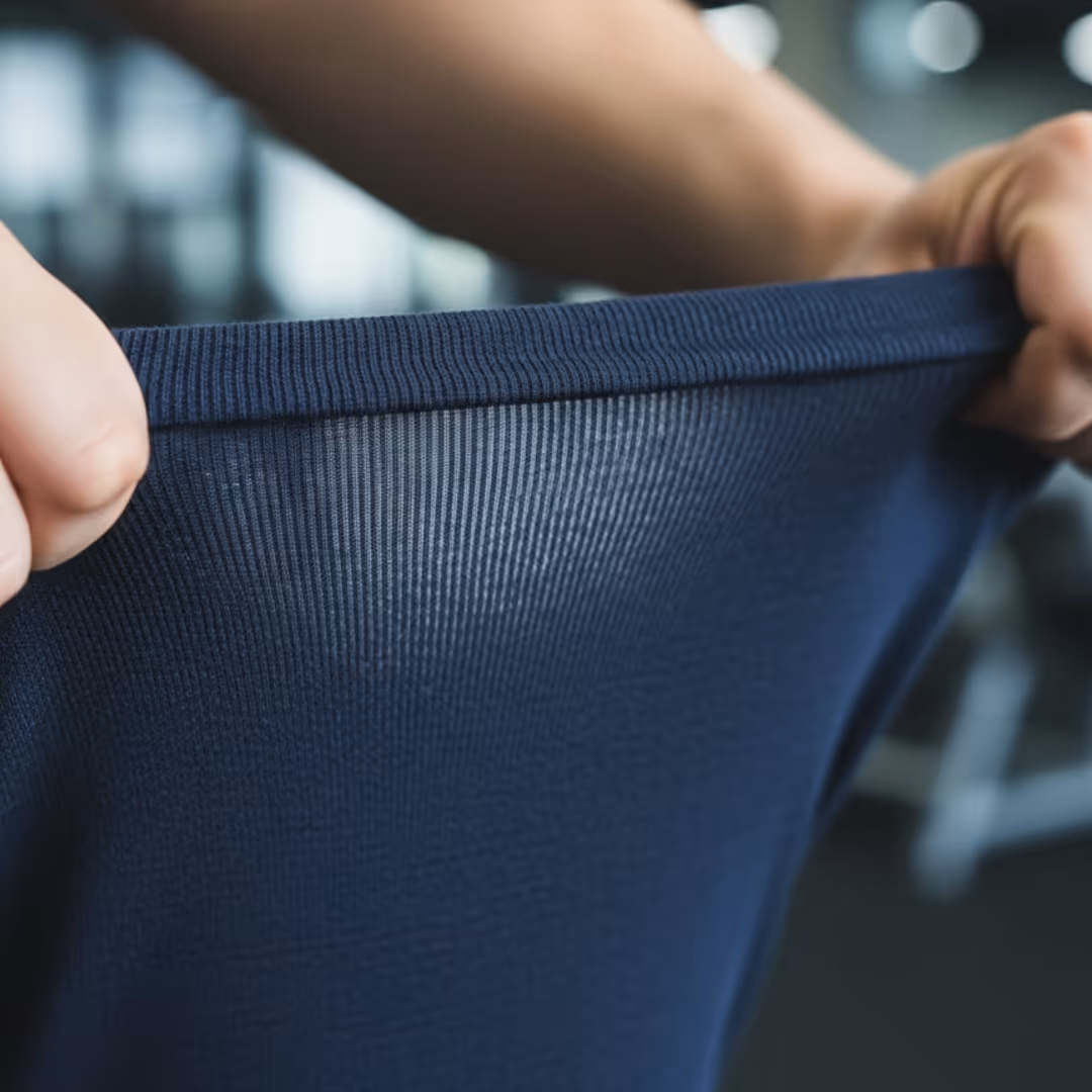 Close-up of hands stretching a piece of dark blue ribbed fabric.