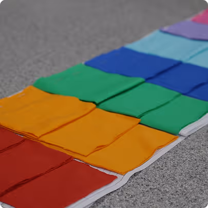 Folded colorful clothes arranged in rows on a speckled gray surface.