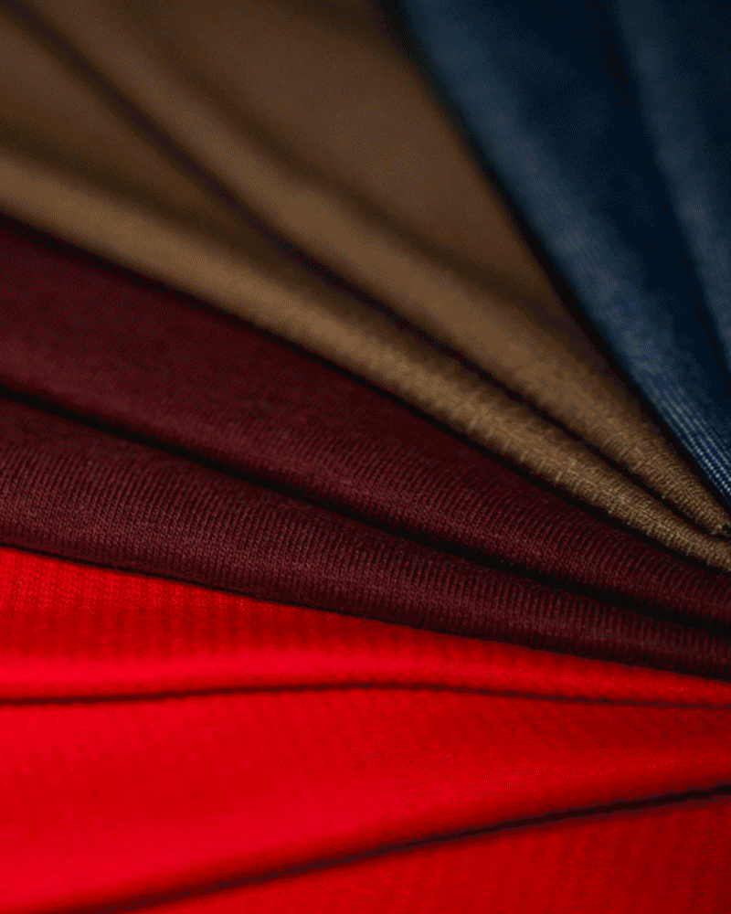 Close-up view of folded fabric in red, maroon, brown, and blue colors arranged fan-like.