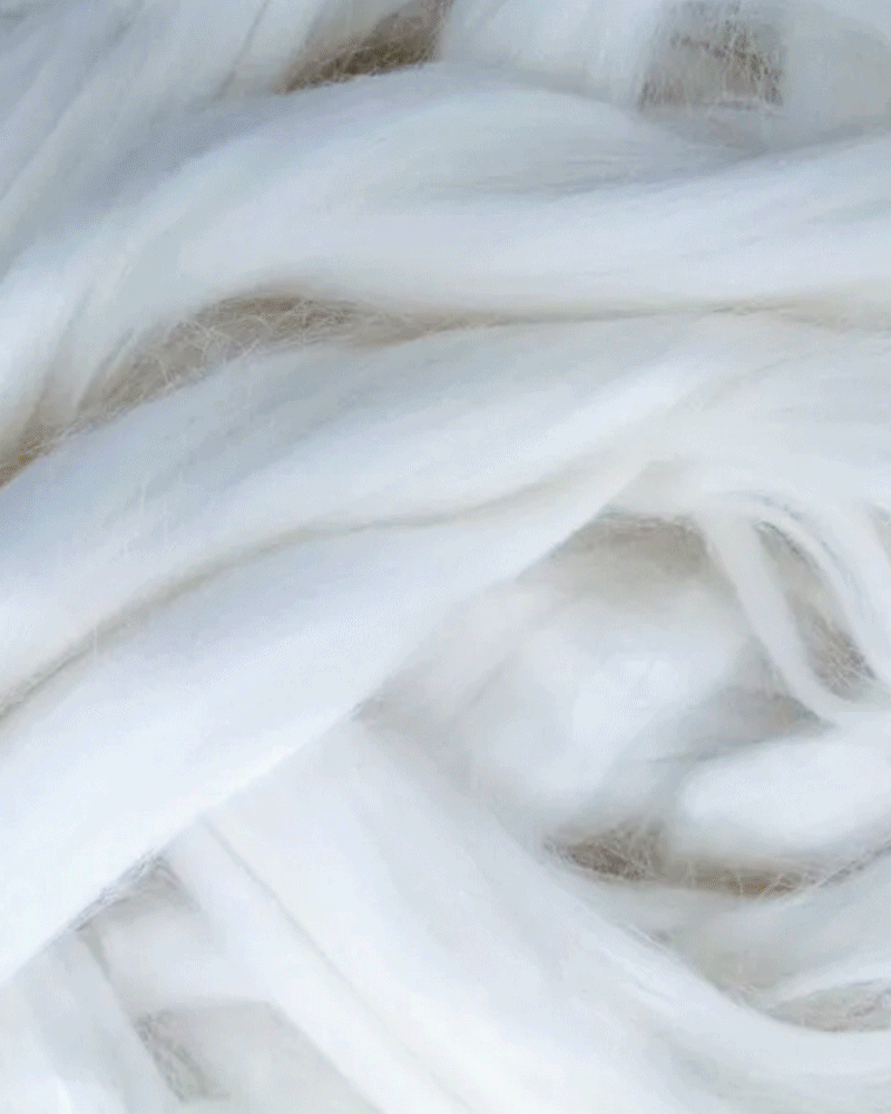 Close-up of white wool fibers being spun into yarn.
