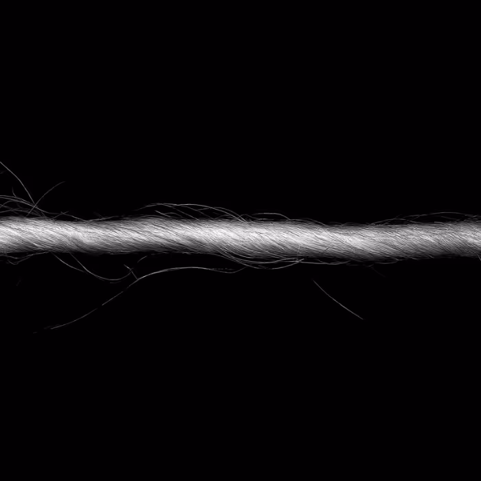 Close-up of a twisted white rope with individual fibers visible against a black background.