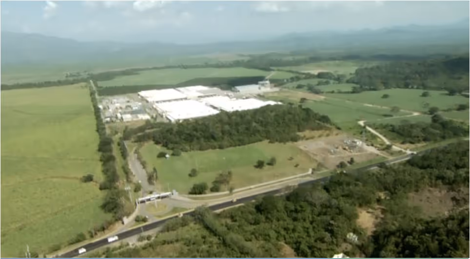 Close-up of an industrial textile machine with white spools of thread and mechanical components in a factory setting.