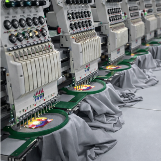 Worker handling a large roll of white fabric on a cutting table inside a spacious textile factory.