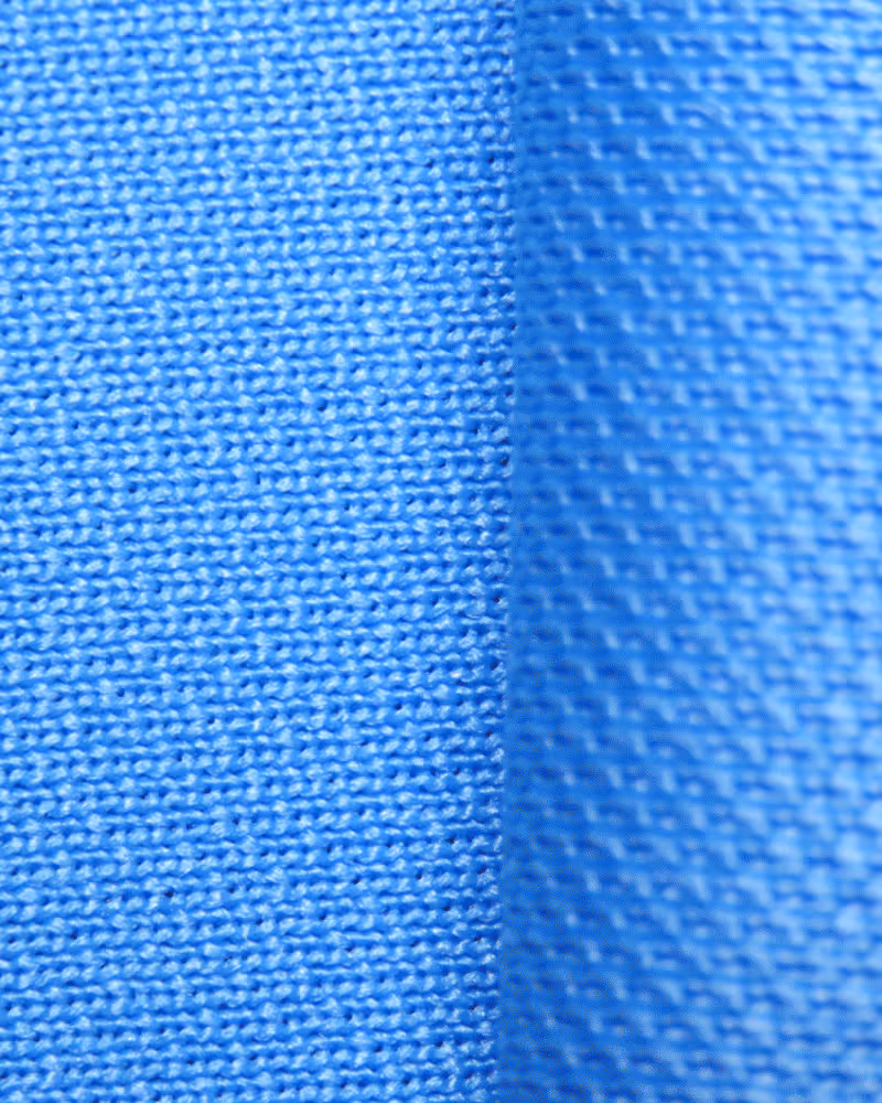 Large spool of white yarn mounted on industrial textile machinery in a factory setting.