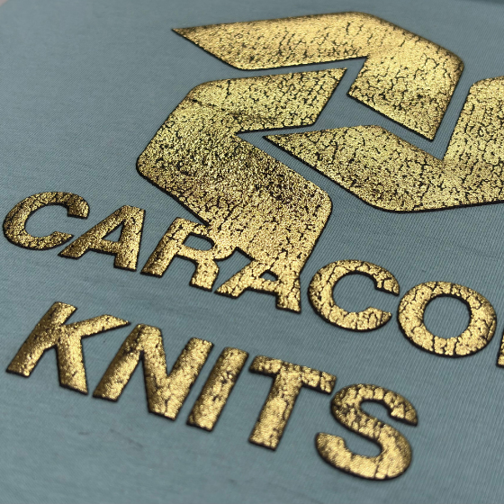 Man handling large rolls of white fabric in a spacious textile factory with industrial machines and bright overhead lighting.