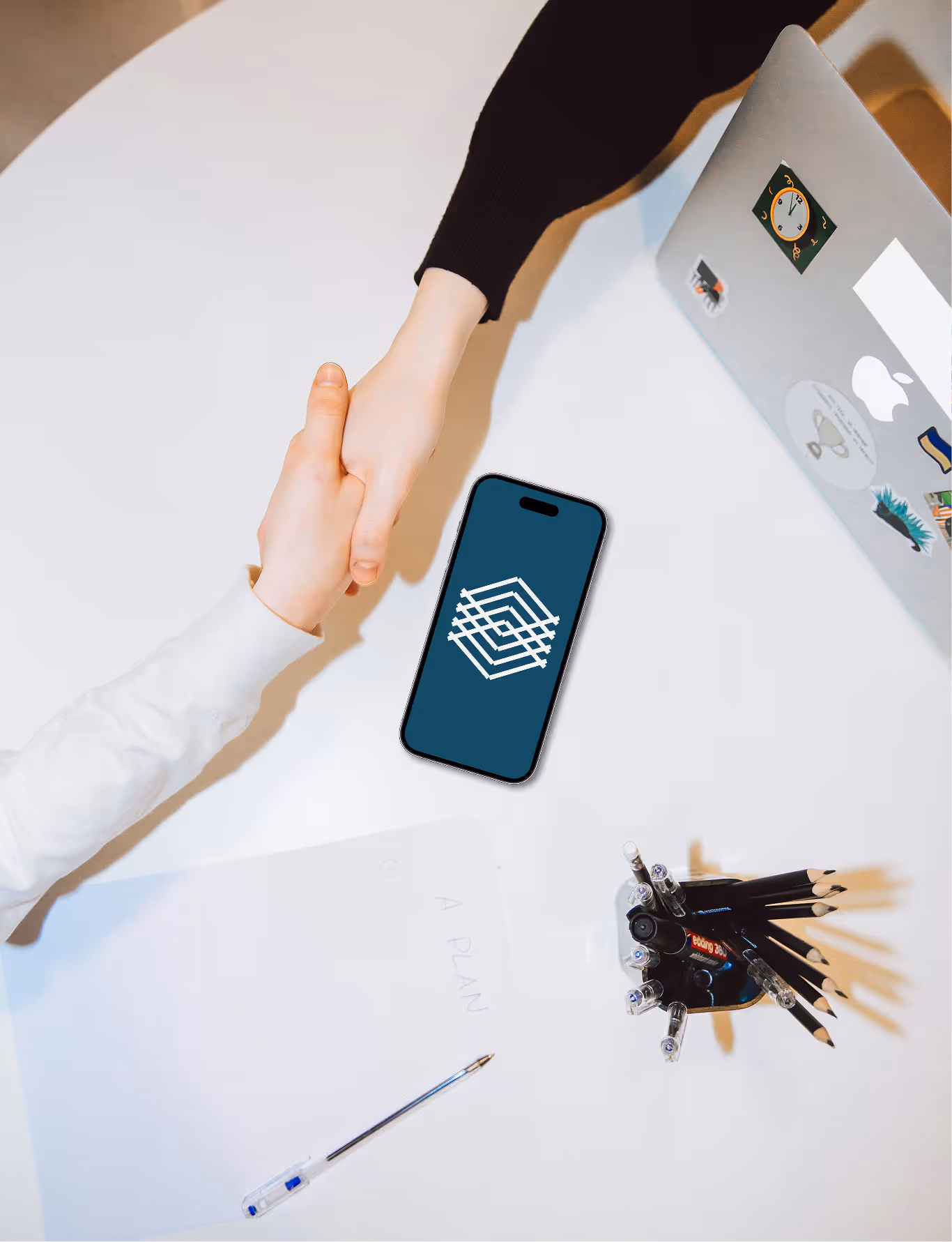 Two people shaking hands above a table with a phone showing idity logo.