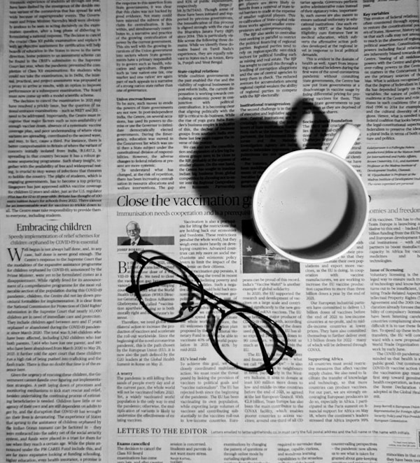 A cup of coffee with a pair of glasses on editorial page of newspaper.