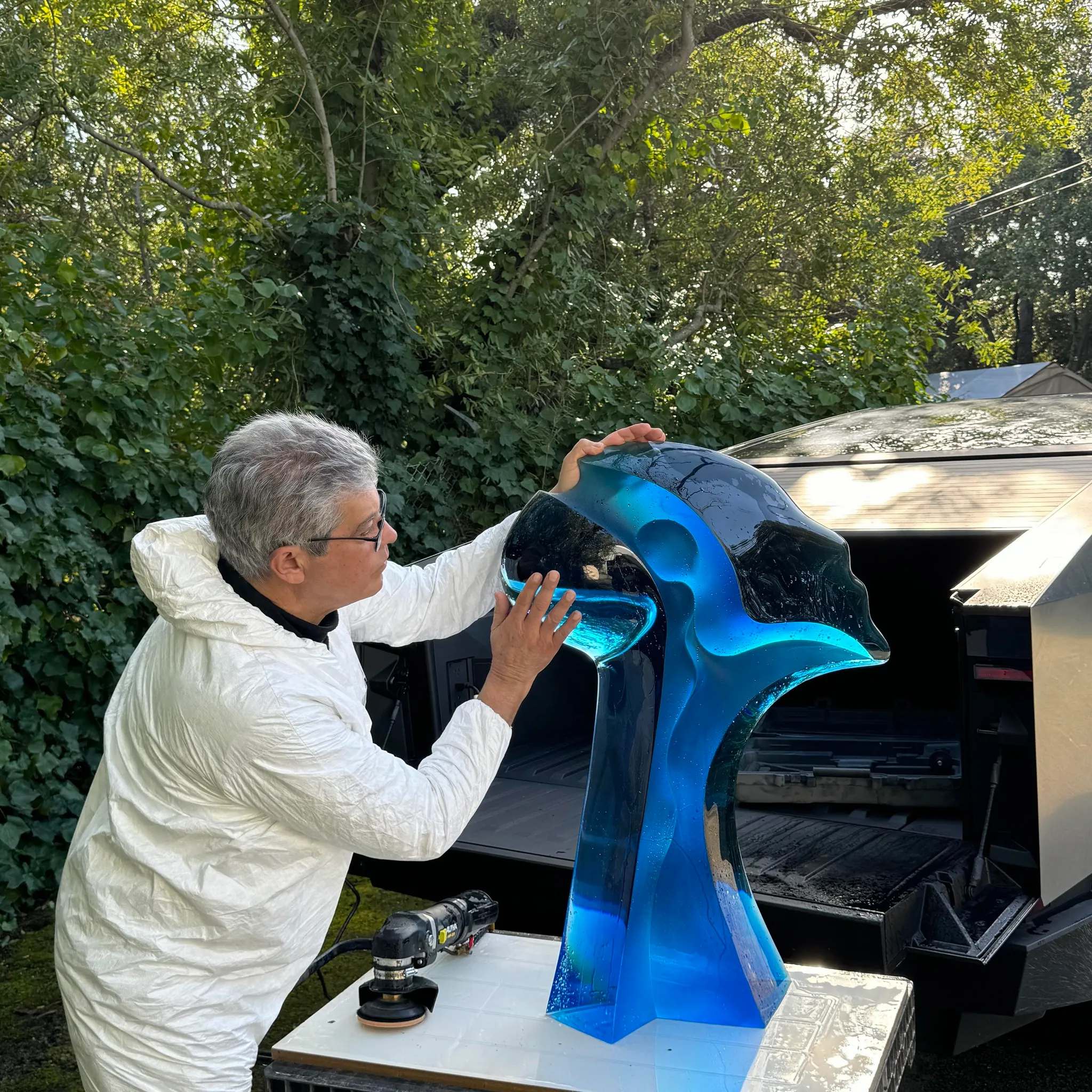 Artist preparing a blue sculpture for transport outdoors