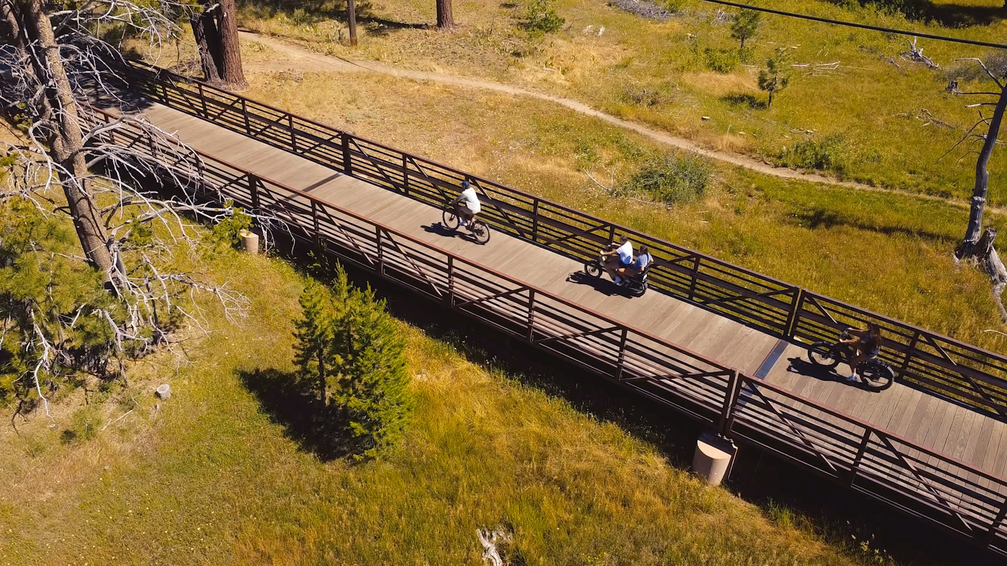 Tahoe boardwalk bike trail fly over view with bikers riding over the bridge that extends the boardwalk over the meadow.