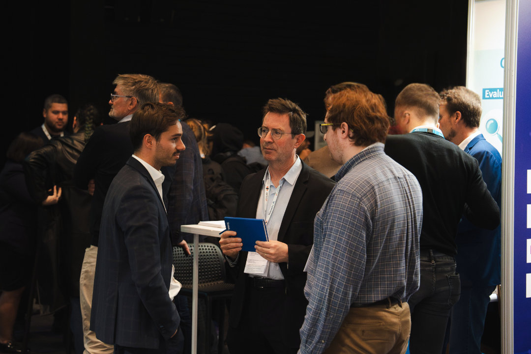 Groupe d'hommes discutant lors d'un événement professionnel intérieur.