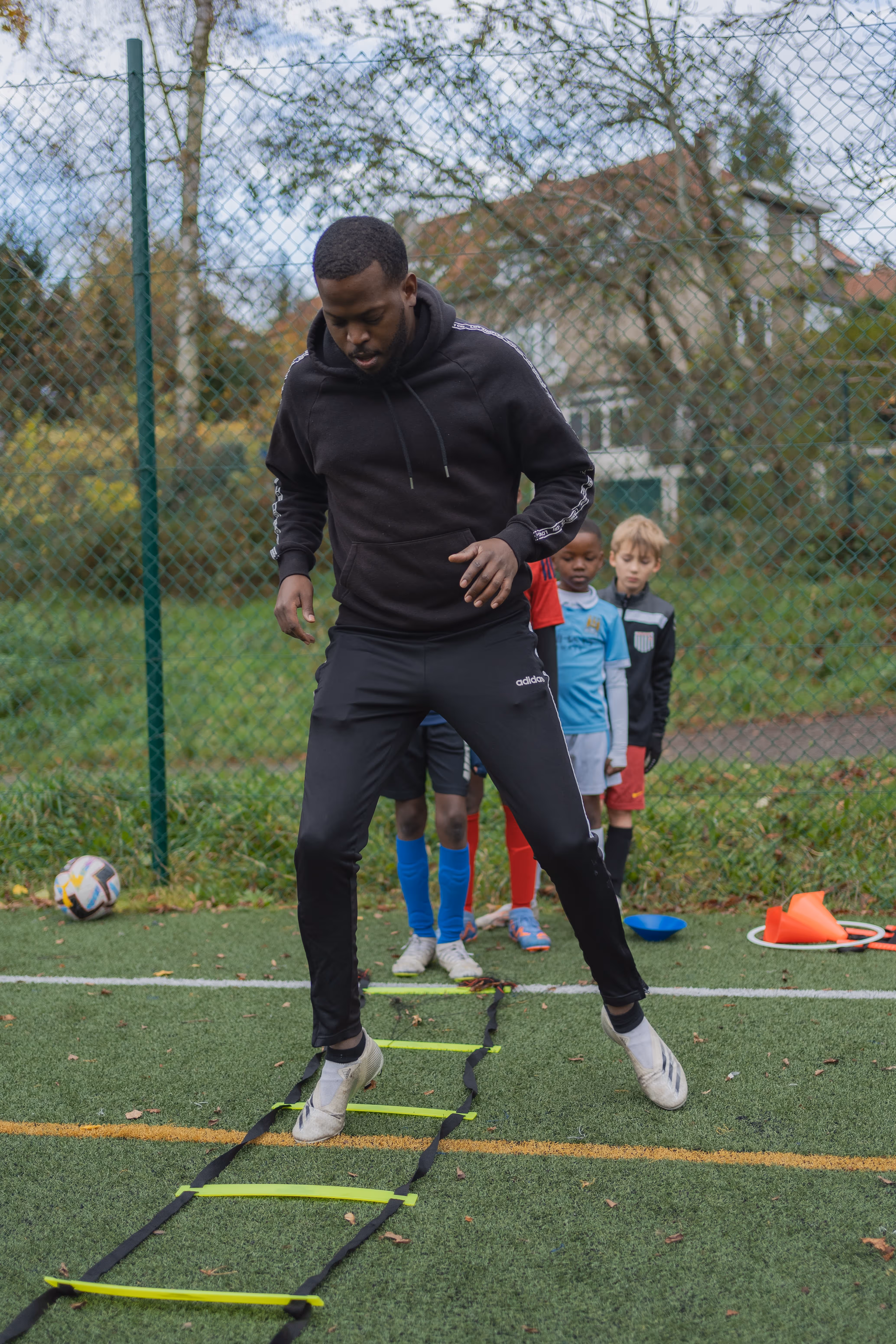 photo coach Patrick qui montre aux enfants un exercice de coordination aux enfants sur un terrain de football