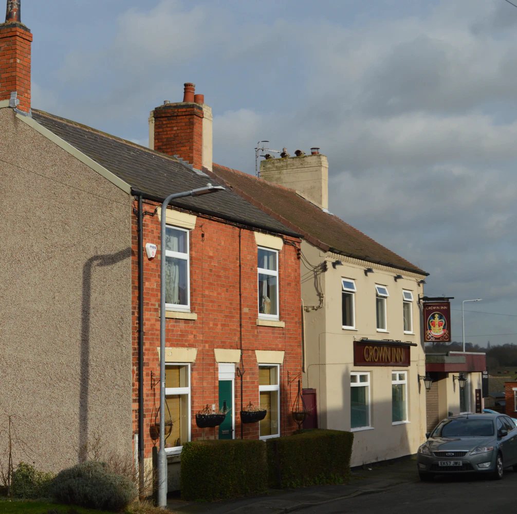 Row of brick and cream-colored buildings with a sign reading 'CROWN INN'.