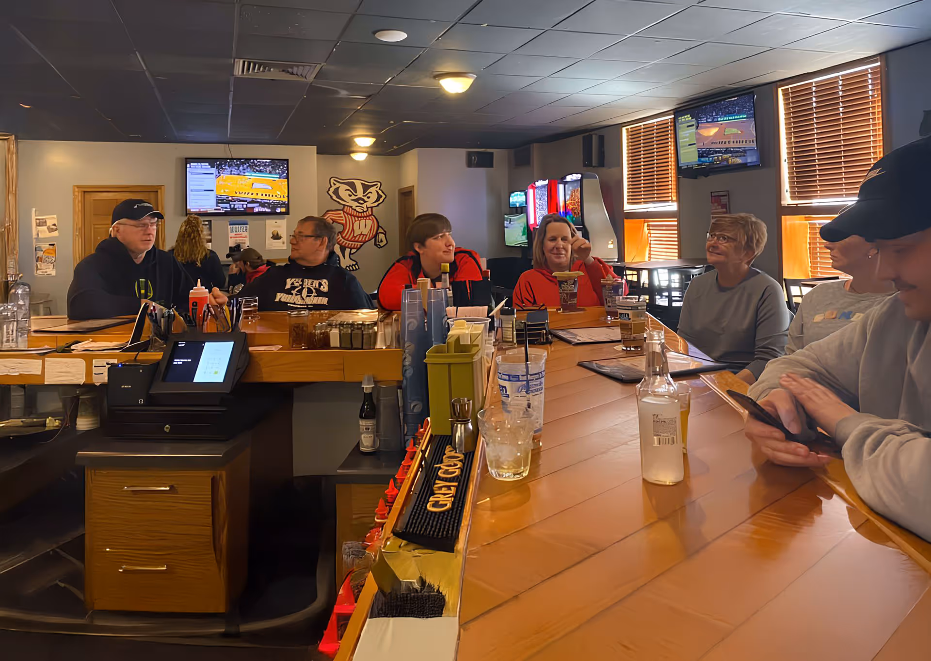 Several individuals sitting at a bar, socializing and sharing drinks in a lively atmosphere.
