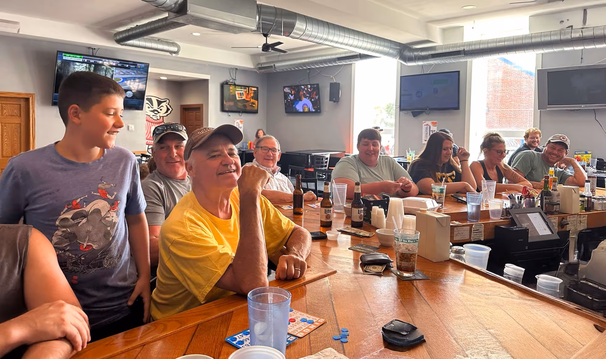 Several individuals gathered at a bar, engaged in conversation and laughter.