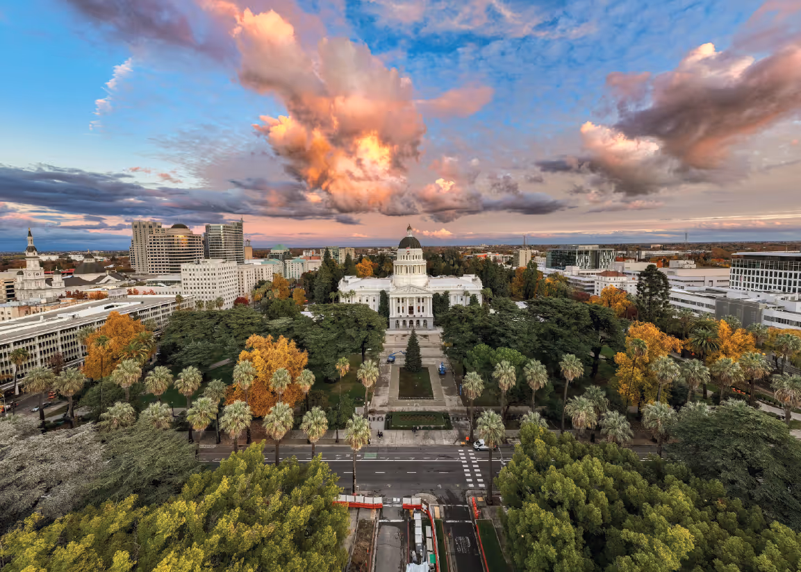 Aerial view of the California State Capitol in Sacramento with dramatic sunset clouds