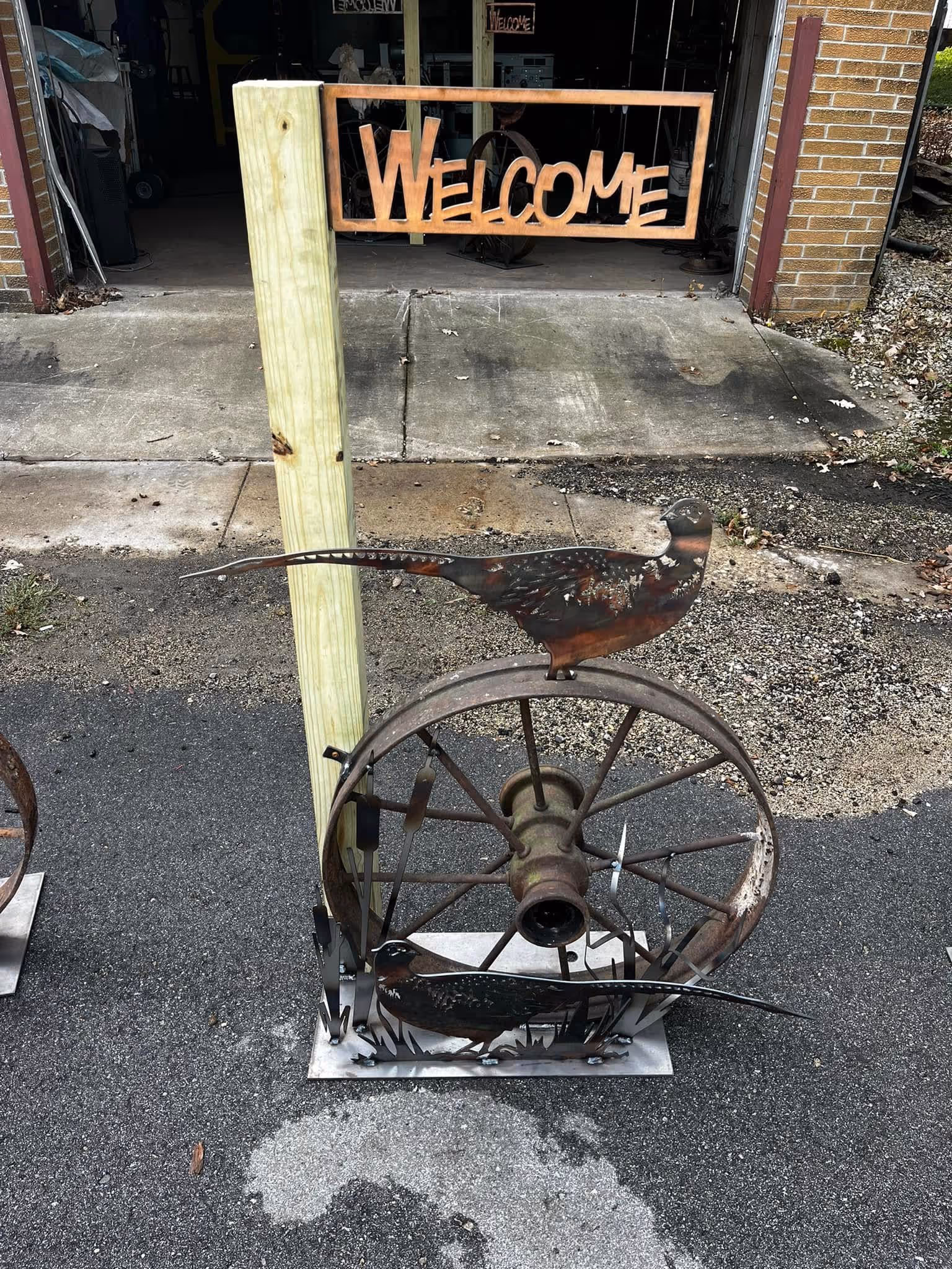 metal and wood welcome sign with a pheasant on a metal spoked wheel