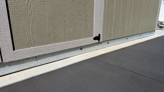 Close-up of the shed base showing floor construction, metal skids, and lower wall trim