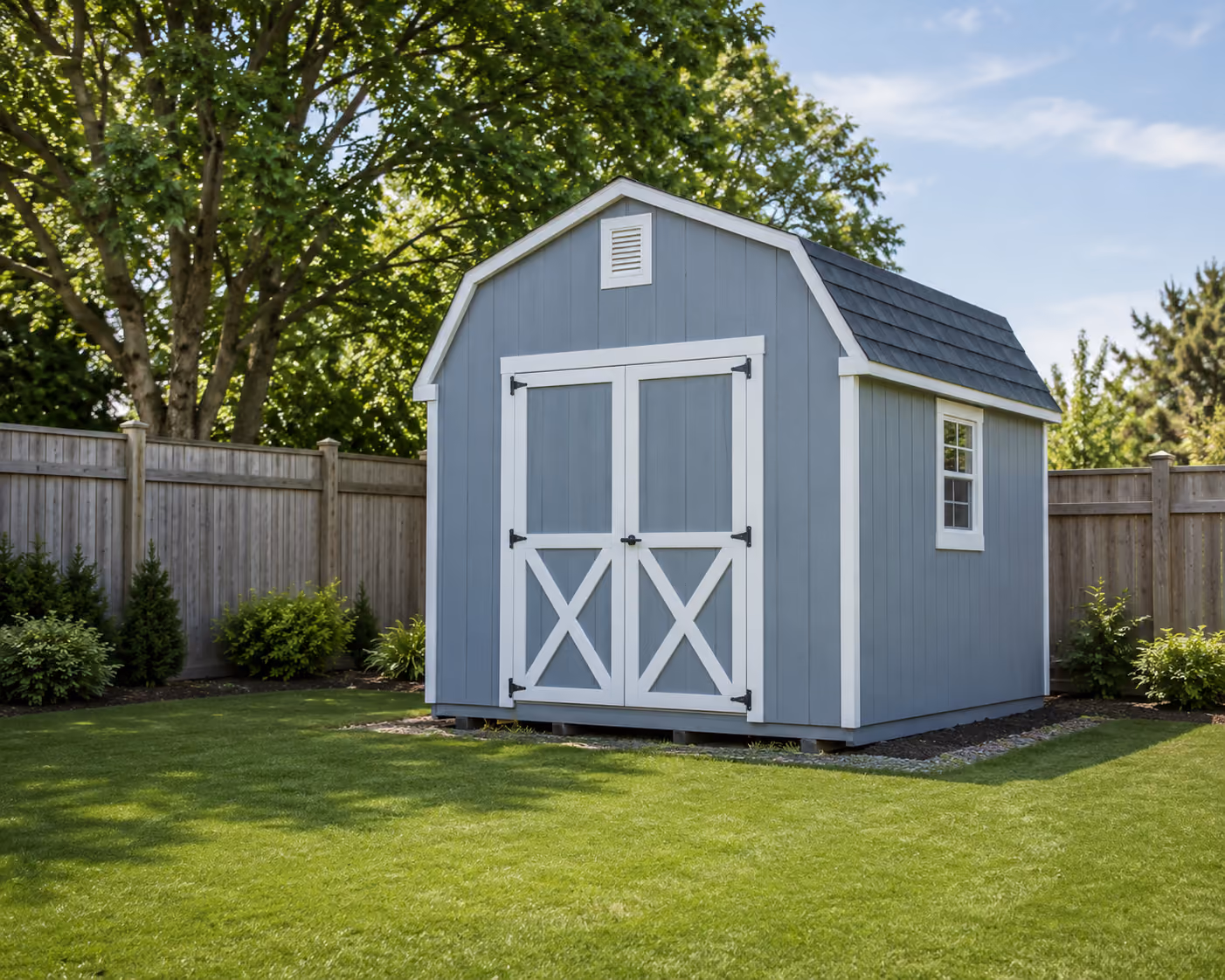 Gray barn-style storage shed with white trim and double doors in a landscaped backyard.
