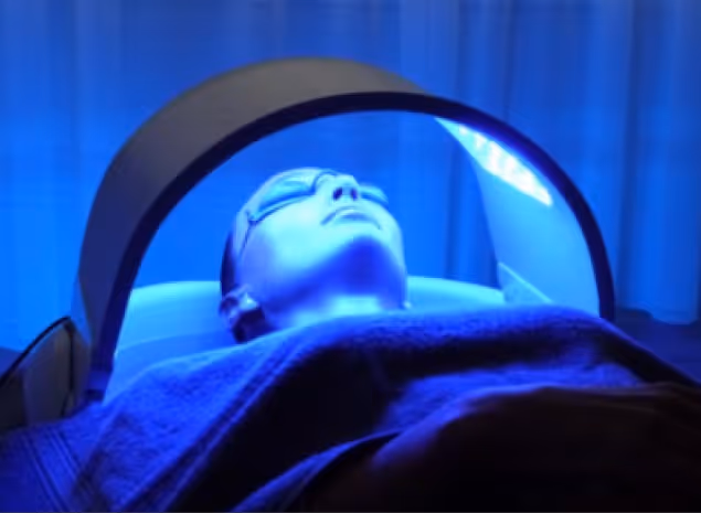 Person receiving a skincare treatment under a blue light at Natural Beauty by Helen clinic in Twickenham, London.