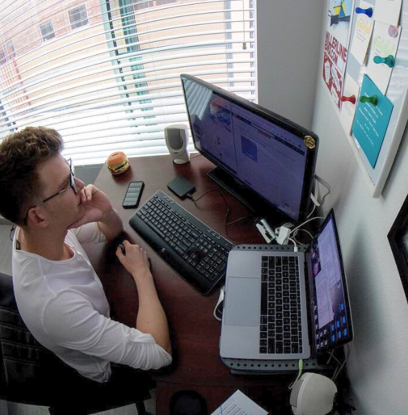 Brandon Miller sitting at desk looking at two computers