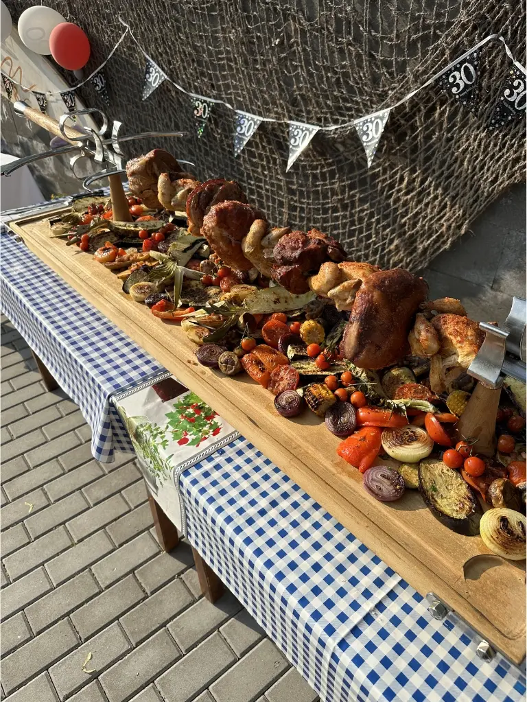 Grilované maso a zelenina na dřevěném pultu při venkovním cateringu