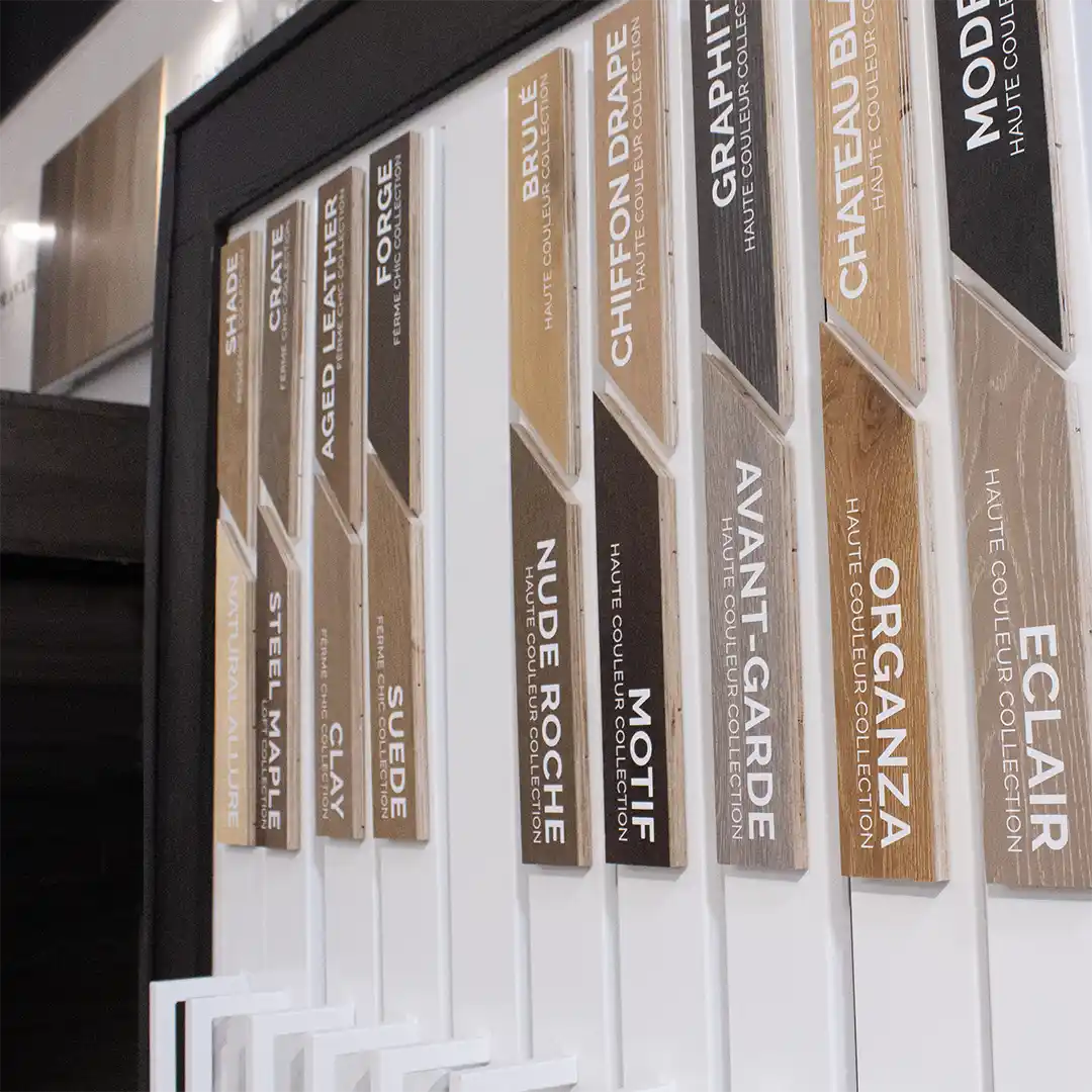 A white metal rack with large wooden magnets on it. The magnets are labelled with white stickers with product names plus collections written below each name in smaller fonts. The image features various wood colours and the magnets fit together in an angular cut.