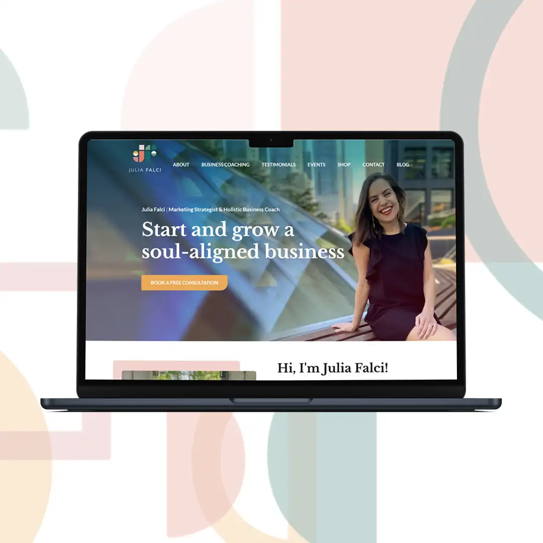 A laptop featuring the hero image of Julia Falci's website designed by Joy. The her shows Julia smiling while sitting on a bench outdoors by a glassy dome. The title says "Start and grow a soul-aligned business".