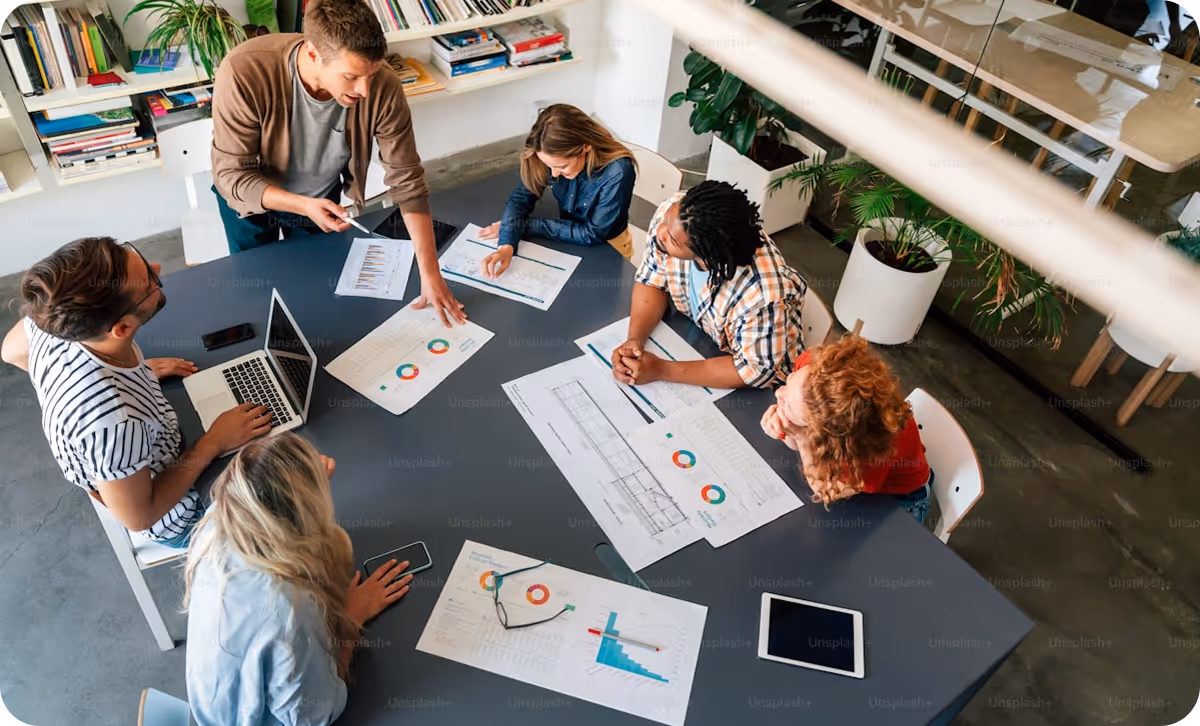 Group of people collaborating around a table with charts.