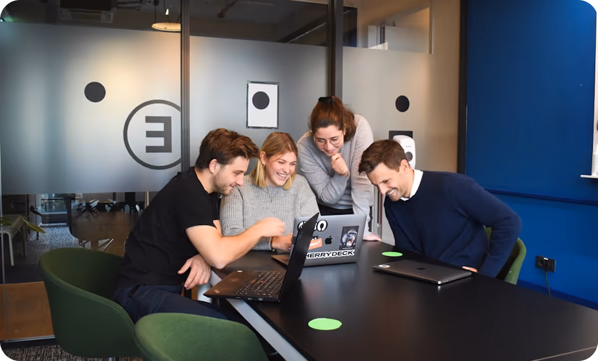Team of coworkers smiling and looking at a laptop.
