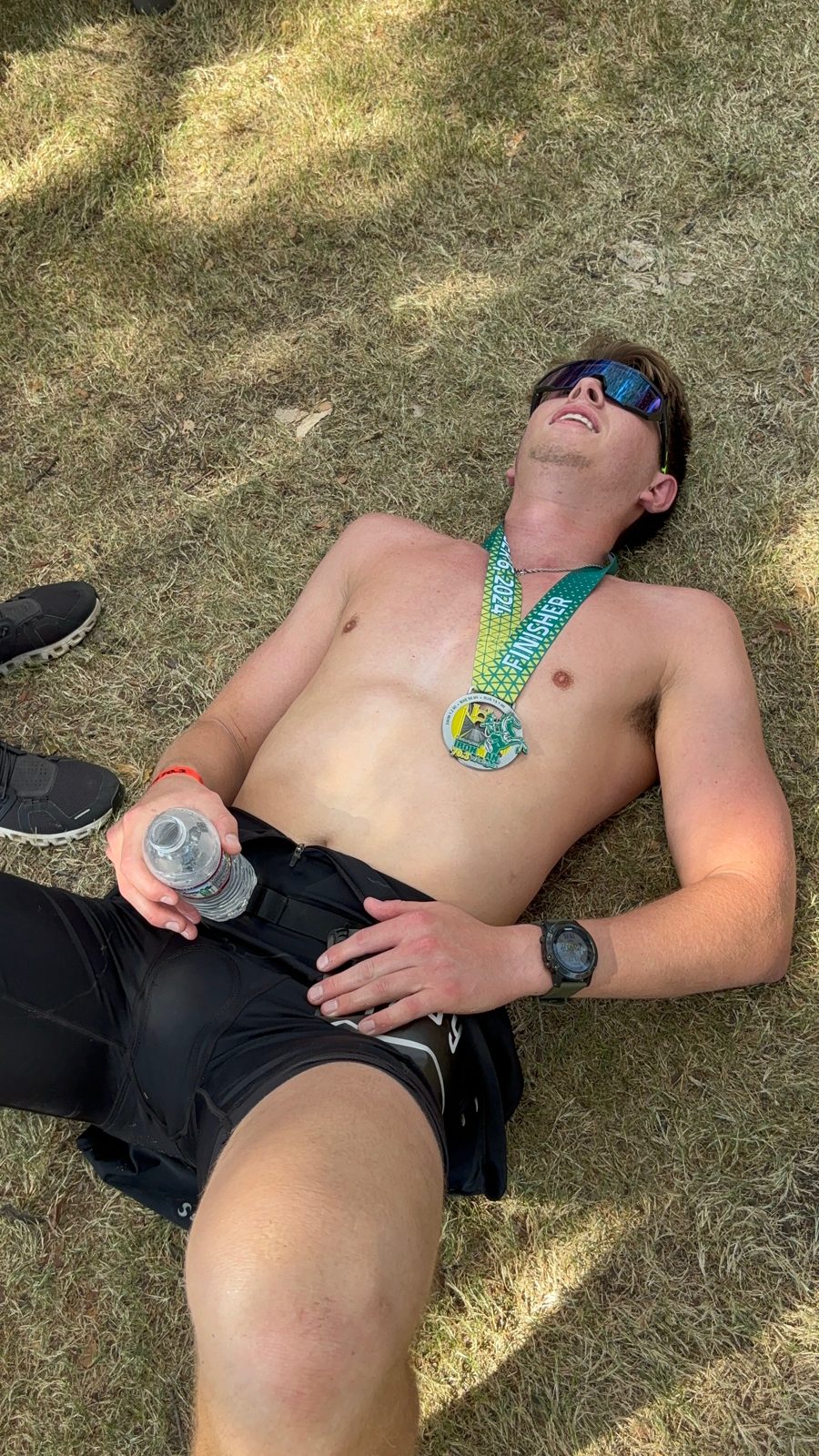 Zach resting on the grass with his medal