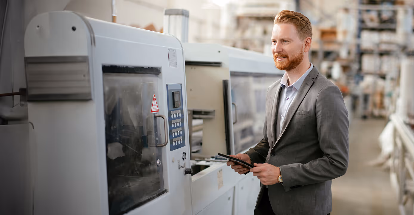 Guy standing in front of a machine in a manufacturing setting