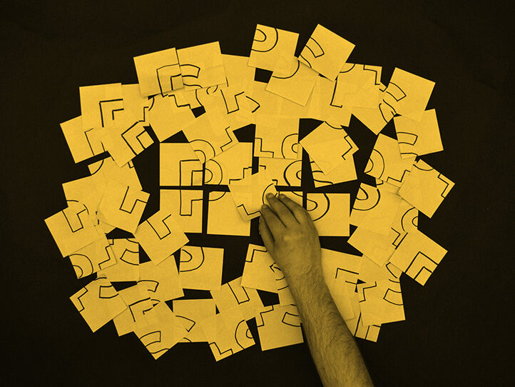 Post it notes being arranged into a word P+S representing explaining and explainer videos.