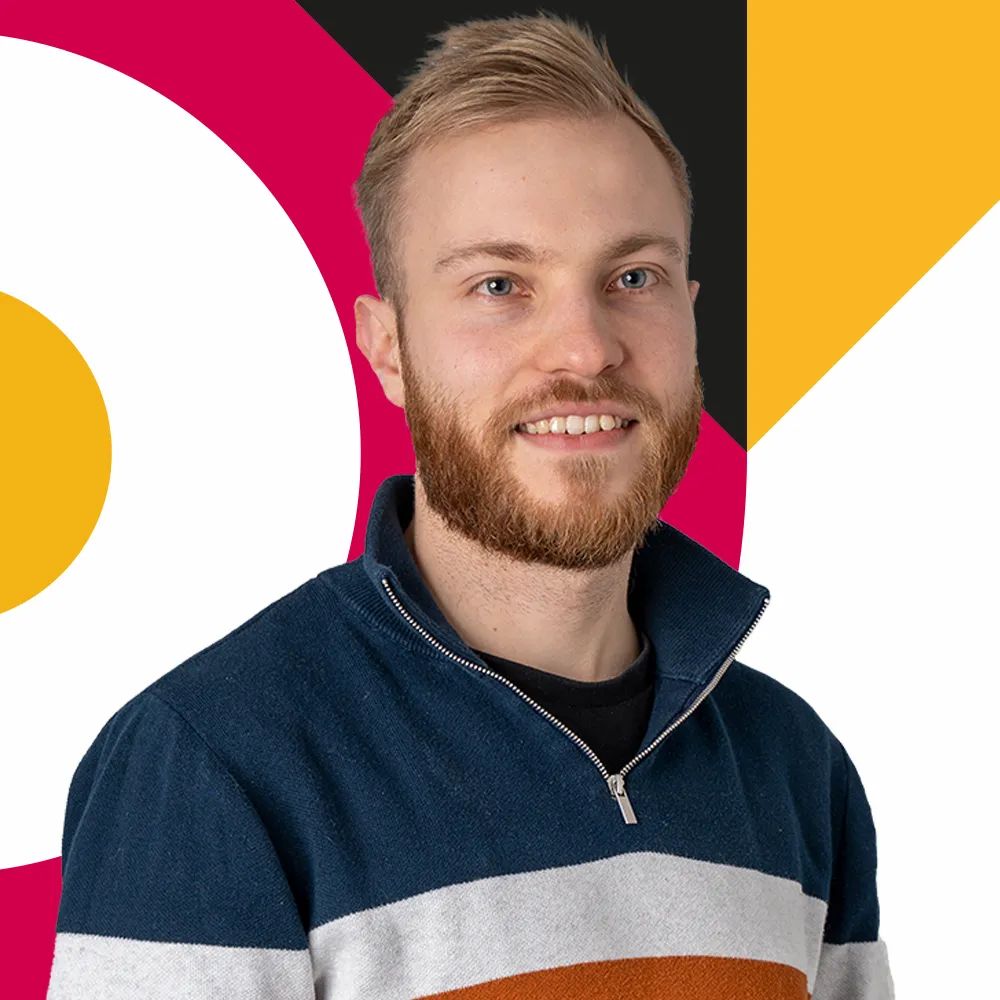 Smiling man with beard wearing a blue, white, and orange striped sweater on geometric background.